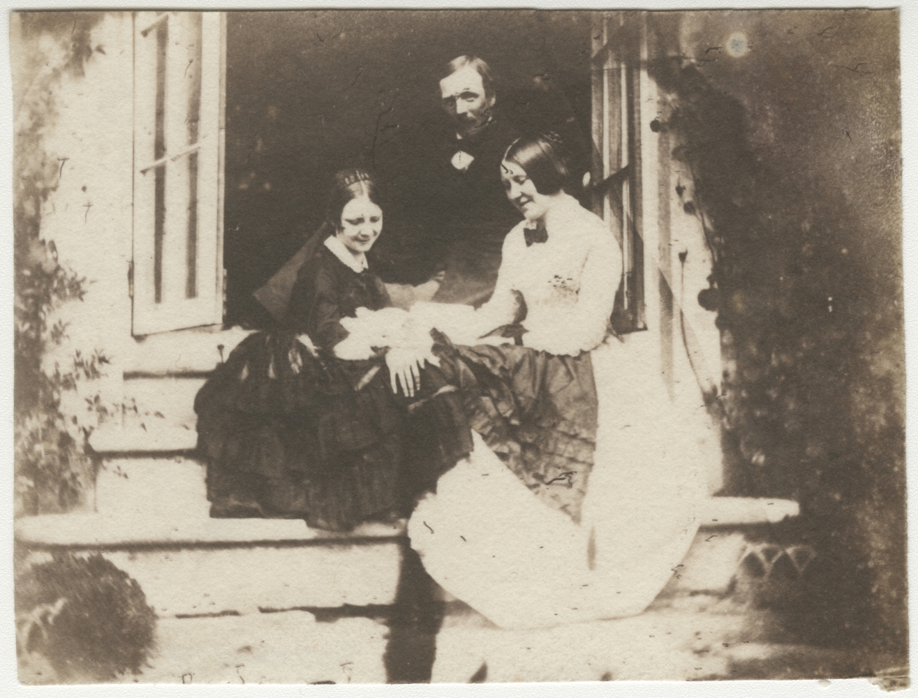 Rev. Calvert Richard JONES (Welsh, 1802-1877) Two ladies and a gentleman, seated on steps, likely at Veranda, early 1850s Salt print from a glass negative 7.6 x  x 10.2 cm
